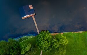 Blue wooden house on body of water near green trees