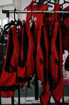 Red life vests arranged on a clothesline indoors for safety and organization.
